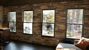 A room with a stone wall, large windows, a white sofa, and a wooden desk. - Little Bit Farm - Create your own stay (Canton)