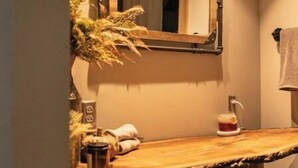 A bathroom with a wooden vanity, a mirror, and a shelf with towels. - Little Bit Farm - Create your own stay (Canton)