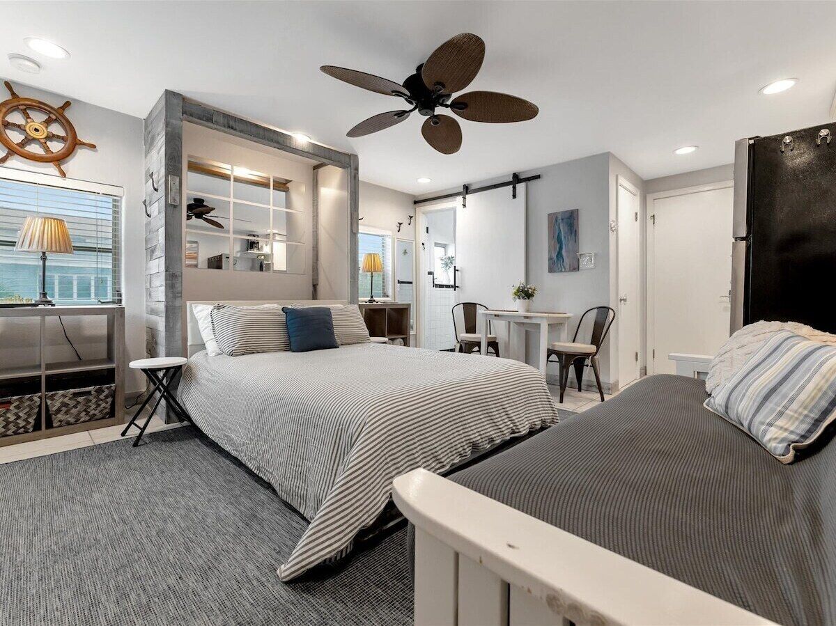 A modern bedroom with a bed, a desk, and a ceiling fan.