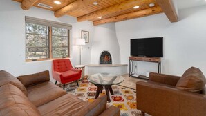 A living room with a fireplace, a television, and a red chair. - Corazon Condo Unit 2, 2 Bed / 2 Bath, Luxury Style Condo (Santa Fe)