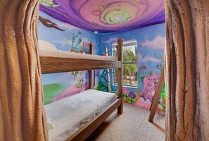 Un lit superposé dans une chambre dont les murs sont décorés de peintures murales colorées.