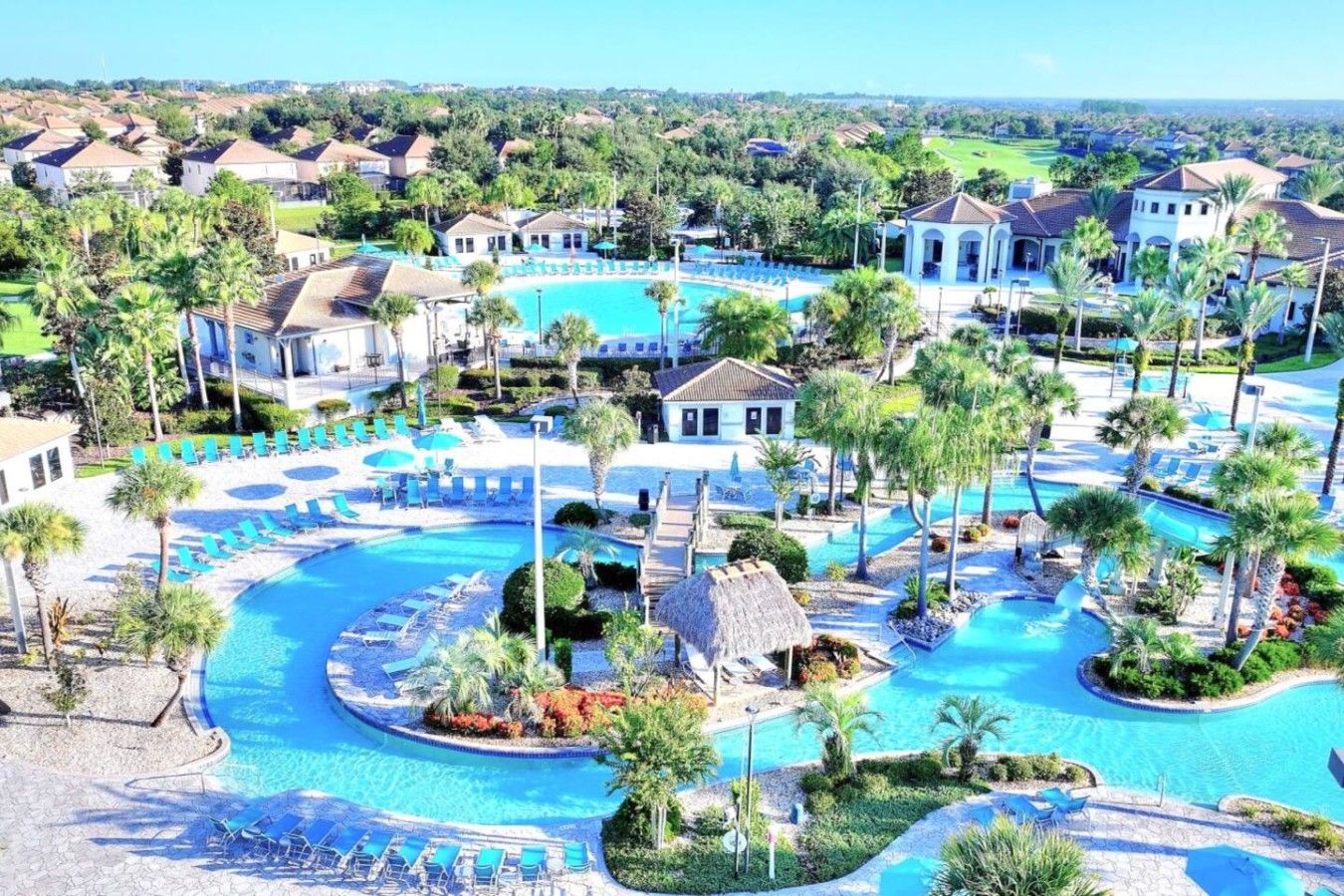 Un resort con múltiples piscinas, palmeras y una variedad de sillas de descanso.
