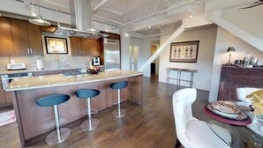 A modern kitchen with a central island, bar stools, and a dining area with a table and chairs. - The Lincoln 501, 2 Bed / 2.5 Bath, Luxury Condo (Santa Fe)
