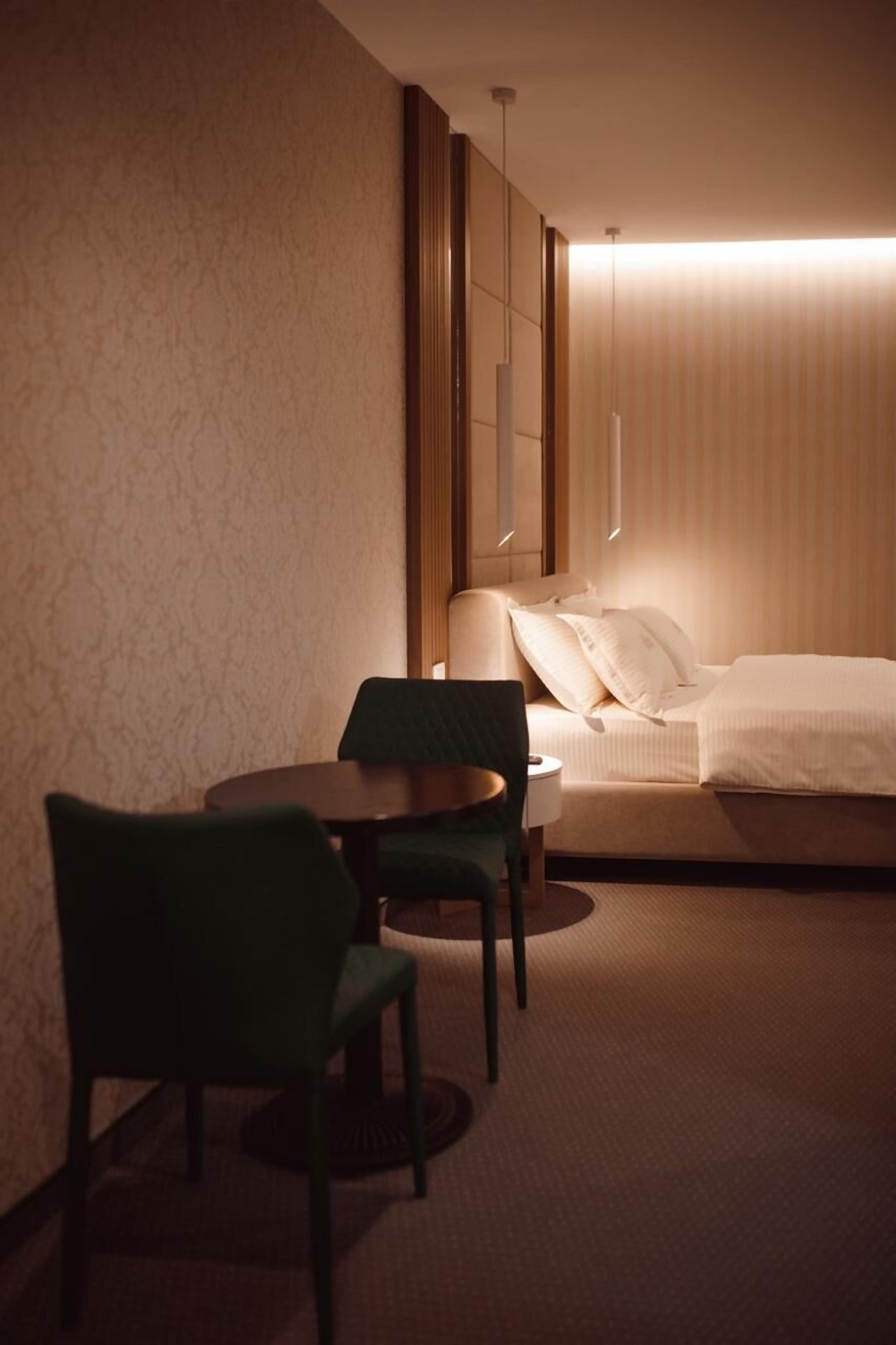 Una habitación de hotel con cama, una silla, una mesa y una lámpara.