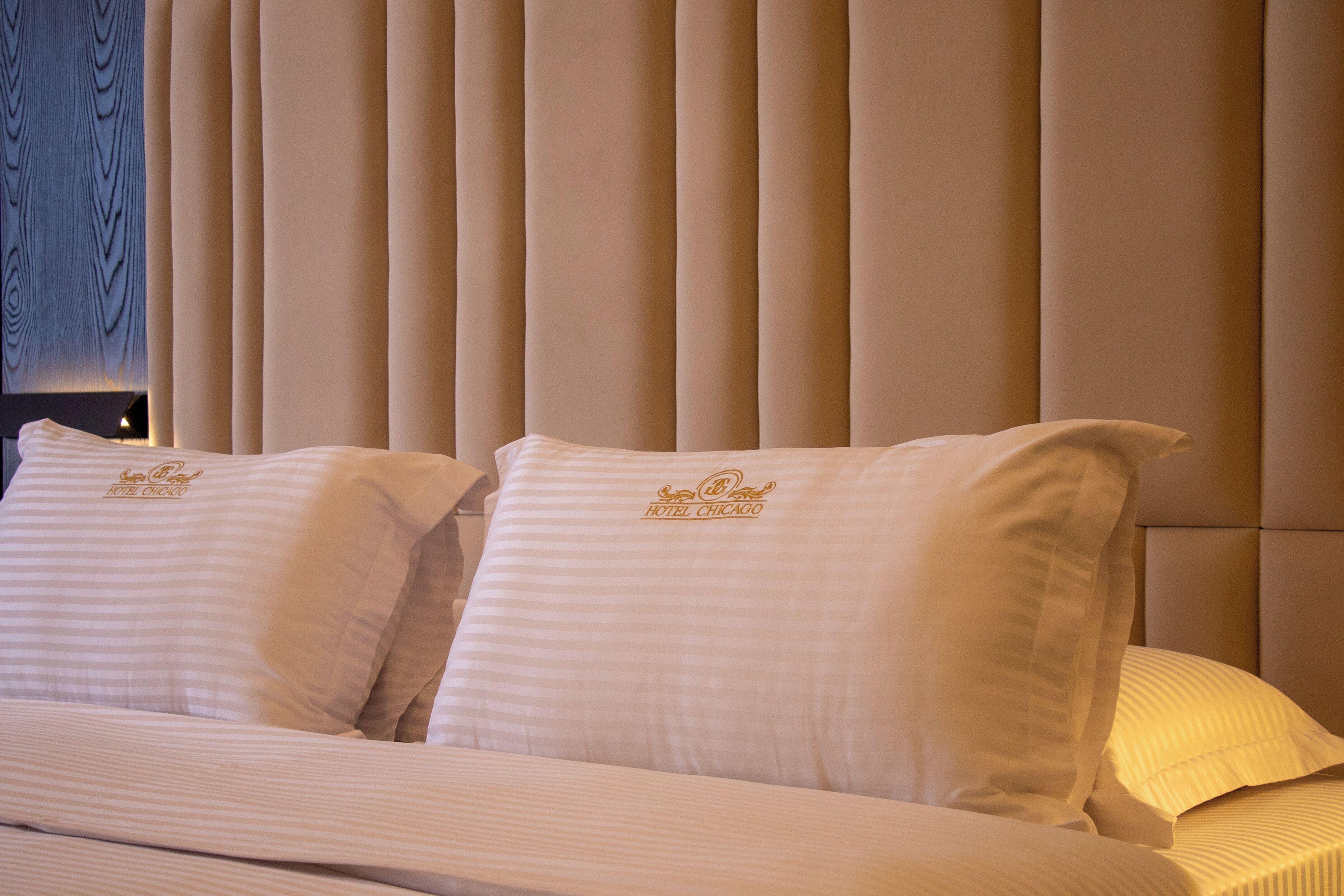 Une chambre d’hôtel avec un lit doté de draps et d’oreillers à rayures, ainsi que d’oreillers portant le logo de l’hôtel.