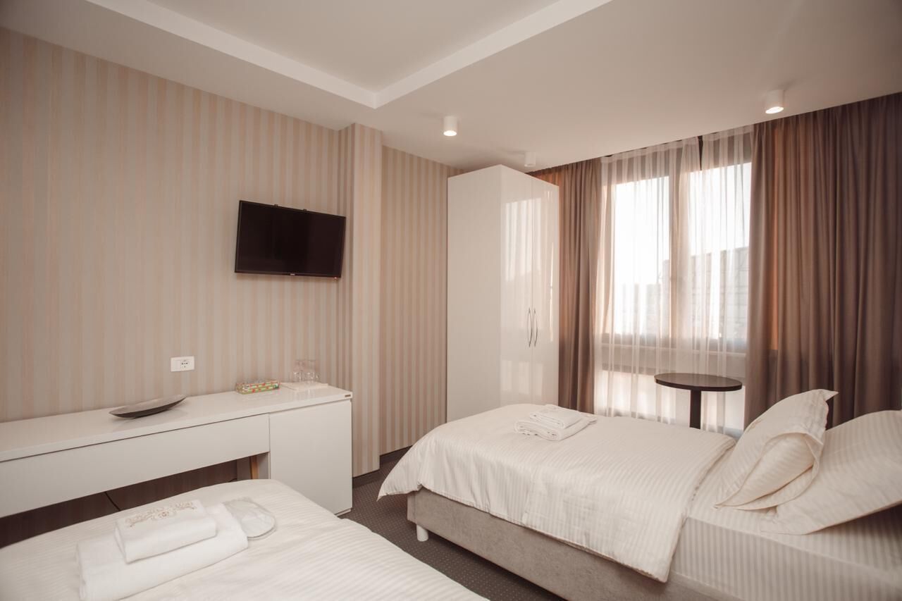 Una camera d'albergo con un letto, un comodino e una TV a parete.