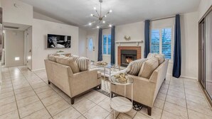 A modern living room with a fireplace, two sofas, a coffee table, and a TV mounted on the wall. - YOUR private Desert Getaway with FREE Heated Pool! (Phoenix)