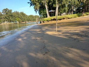 Una playa arenosa con una estructura de madera y un poste metálico.