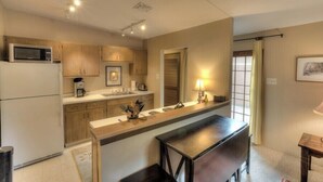 A compact kitchen with a microwave, coffee maker, and a dining area with a table and bench.