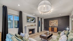 A modern living room with a fireplace, green sofas, a coffee table, and artwork on the walls. - Mid-Century Modern Charmer with FREE heated pool! (Phoenix)