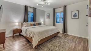A bedroom with a bed, bedside tables, a rug, and a ceiling light fixture. - Mid-Century Modern Charmer with FREE heated pool! (Phoenix)