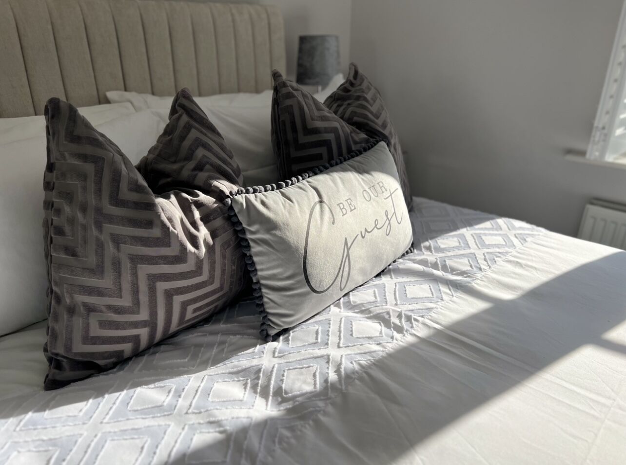 A bed with patterned bedding and decorative pillows, including one with text.