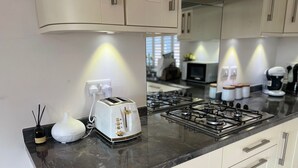 Une cuisine moderne équipée d’une cuisinière à gaz, d’un grille-pain blanc et d’un plan de travail en marbre noir.