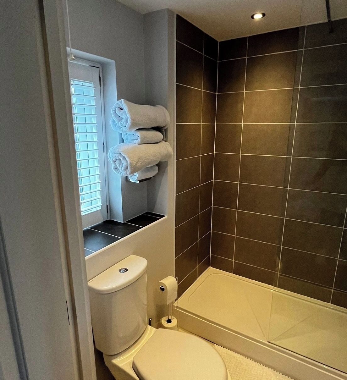 A bathroom with a toilet, a bathtub, and a window with blinds.
