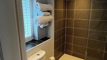A bathroom with a toilet, a bathtub, and a window with blinds.