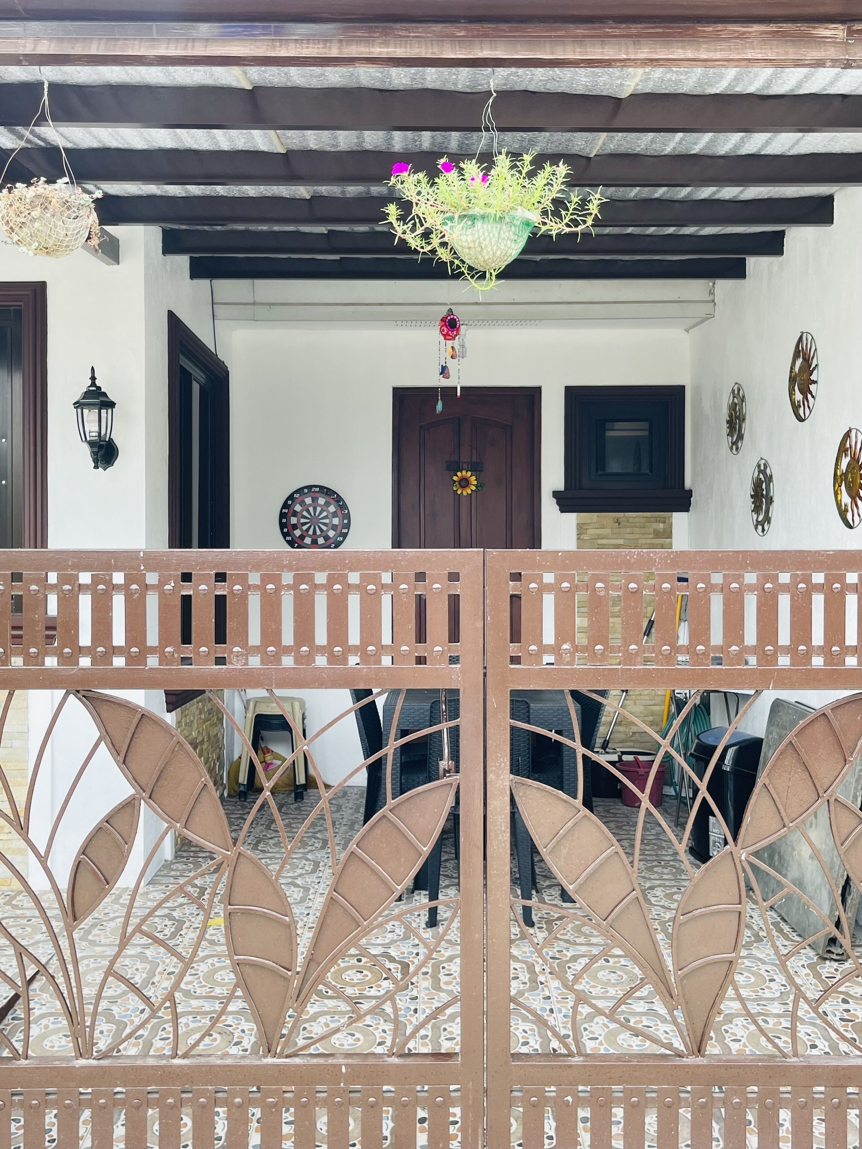 A traditional house with a tiled patio, a wooden door, and a decorative metal gate.