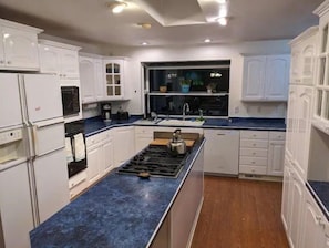 Kitchen features an oven, stovetop, and sink with a window above.