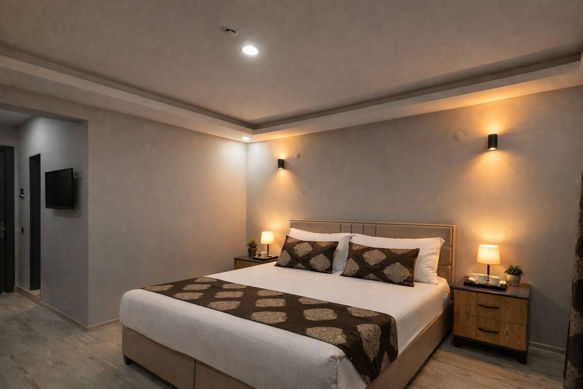 A modern bedroom with a large bed, two bedside tables, and wall-mounted lights.