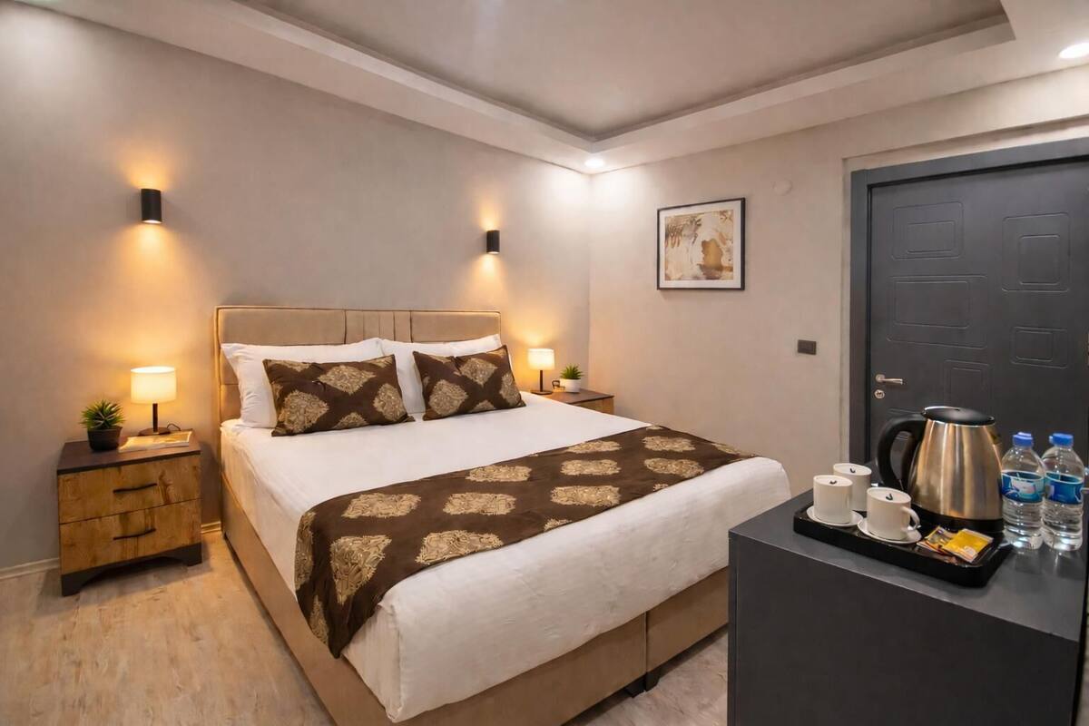 A neatly arranged hotel room with a bed, bedside tables, a coffee station, and a door.