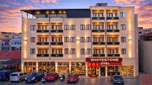 A hotel with multiple floors, balconies, and a prominent entrance with a red awning. - Whitestone Hotel (Ürgüp)