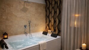 A modern bathroom with a large bathtub, a shower, and a vanity area. - Whitestone Hotel (Ürgüp)