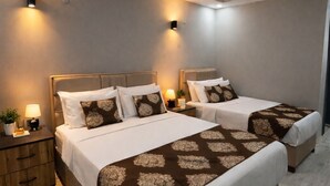 A hotel room with two beds, a nightstand, and wall-mounted lights. - Whitestone Hotel (Ürgüp)
