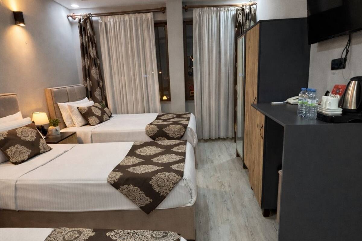A hotel room with two beds, a desk, a TV, and a wardrobe.