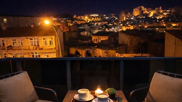 A terrace with two chairs and a table, two cups of coffee, and a lit candle. - Whitestone Hotel (Ürgüp)