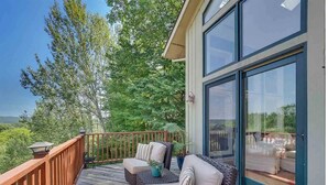 A wooden deck with wicker furniture and a glass door leading to a covered area.