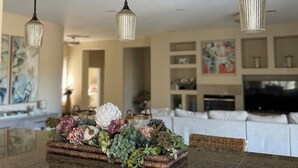 A kitchen island with a decorative centerpiece, three pendant lights, and a modern countertop.