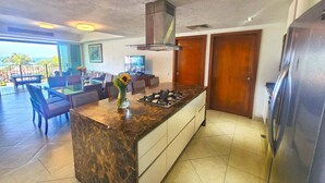 A modern kitchen with a marble countertop, a gas stove, and a stainless steel refrigerator.