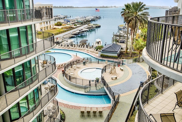 A multi-level hotel with a central pool, outdoor seating, and a marina view.