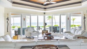 A spacious living room with a large window overlooking a pool and the ocean. - GoldenEye Estates!- GoldenEye + Palm Villas (Freeport)