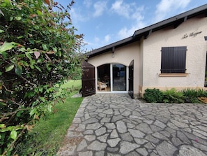 A building with a stone-paved entrance, a glass door, and a window with shutters. - Family Villa for 8 people (Seignosse)