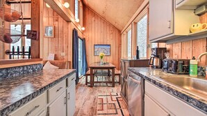 Interior de madera con zona de cocina, que incluye un fregadero, estufa y armarios.
