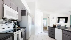 Una cocina moderna con gabinetes blancos, encimera negra y salpicadero de azulejos.