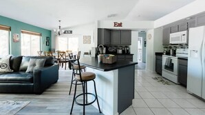 Una cocina moderna con una isla central, un área de comedor con sofá y sillas, y una encimera de cocina con electrodomésticos.