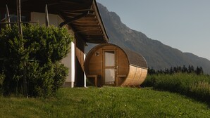 A wooden cabin with a door, a wooden structure with a sloped roof, and a mountain in the background.