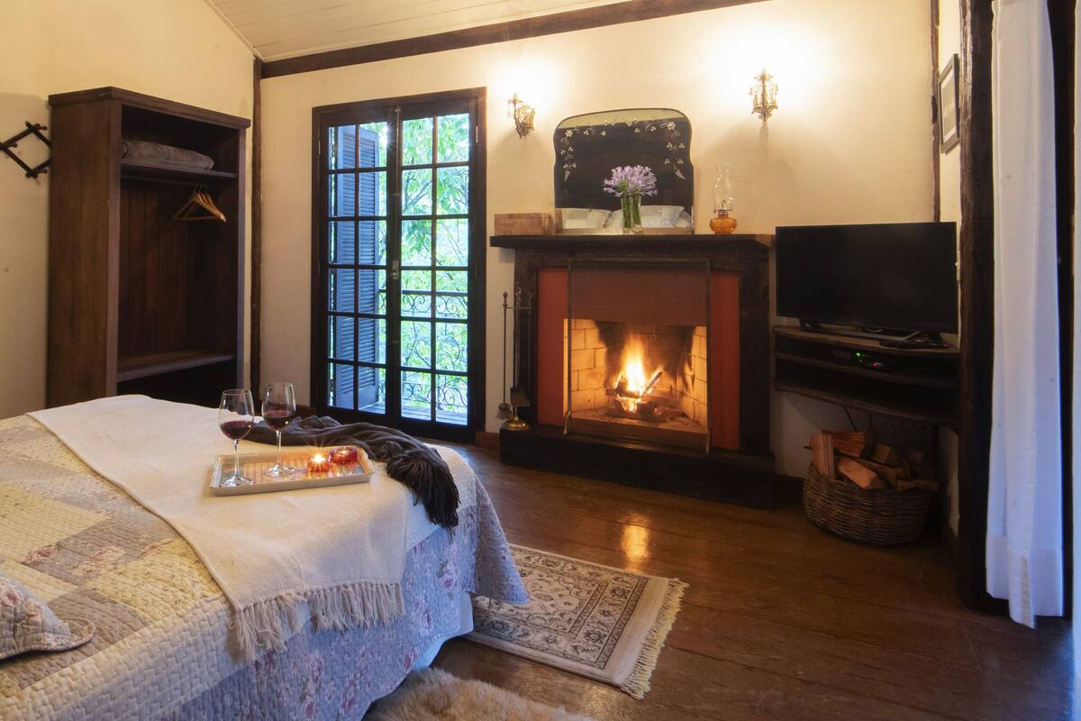 Um quarto acolhedor com cama, lareira e televisão.