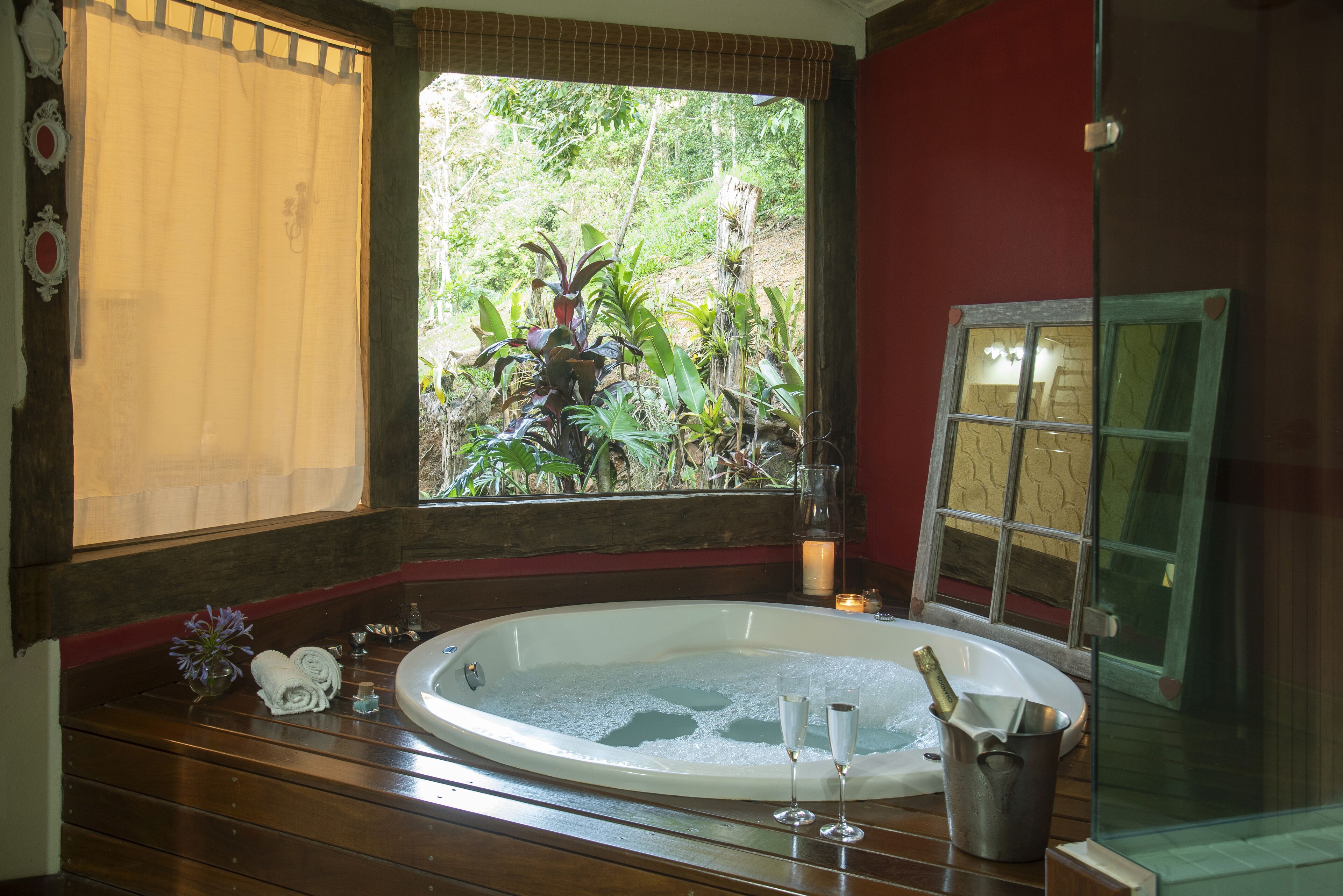A spa room with a large bathtub, a window with a view of greenery, and a glass door.