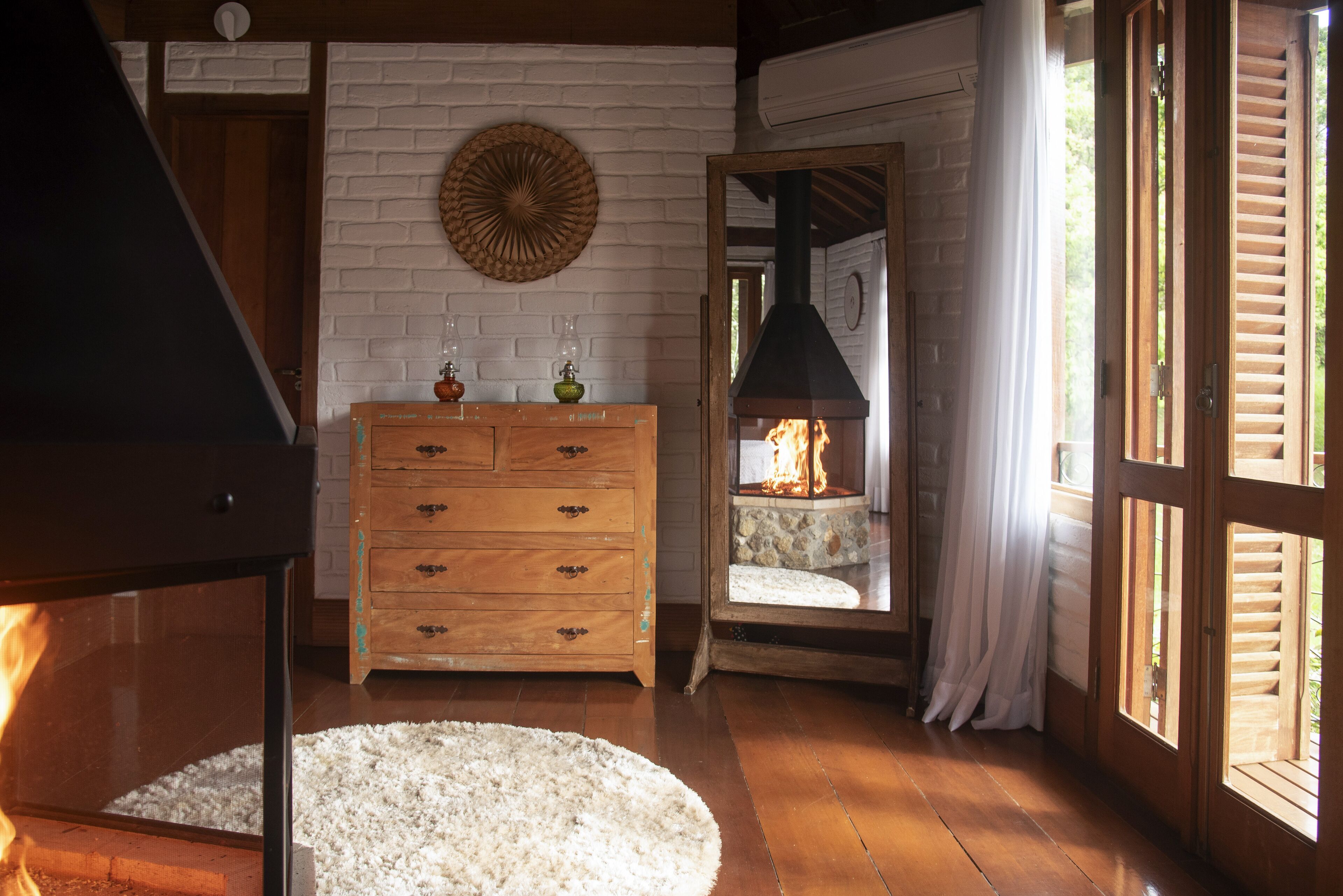 Una habitación acogedora con chimenea, cómoda de madera y un tapete redondo.