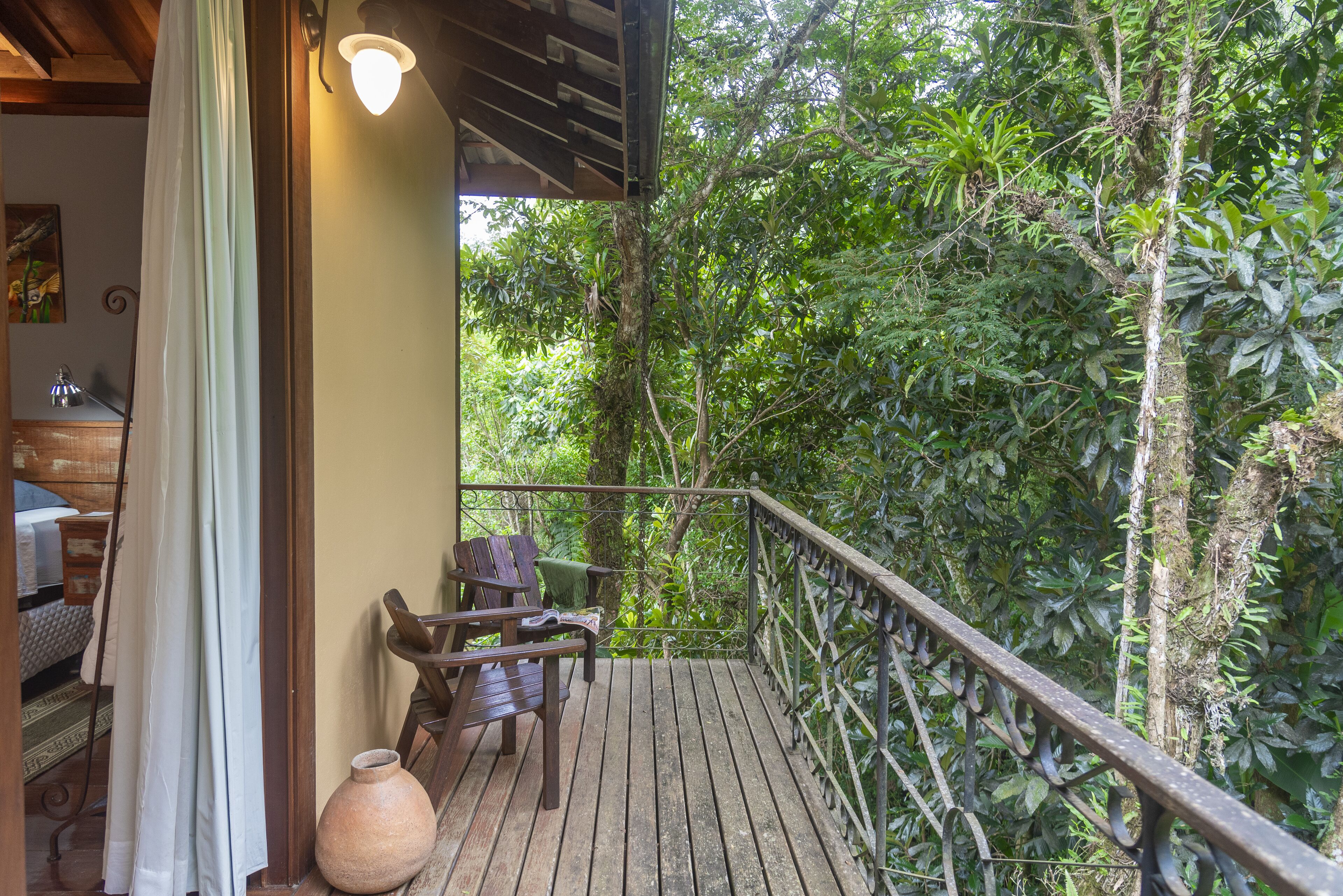 A wooden deck with a railing, a chair, and a vase.