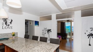 Une cuisine moderne dotée d’un plan de travail en granit, de chaises en osier foncé et d’un coin repas.
