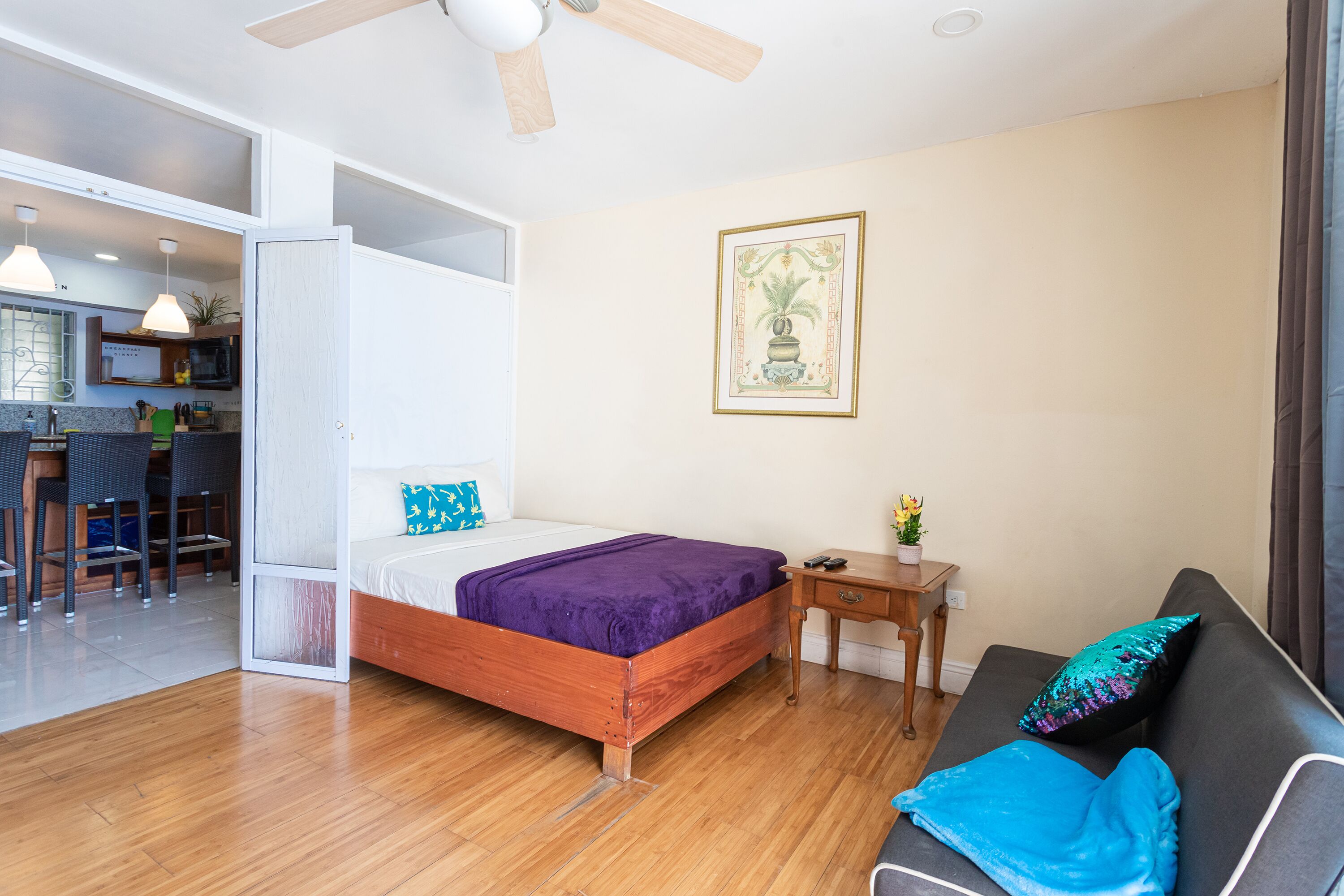 A bedroom with a bed, a sofa, a small table, and a painting on the wall.