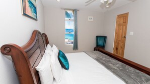 Une chambre à coucher avec un lit, une porte en bois, une fenêtre donnant sur un paysage agréable et un ventilateur de plafond.