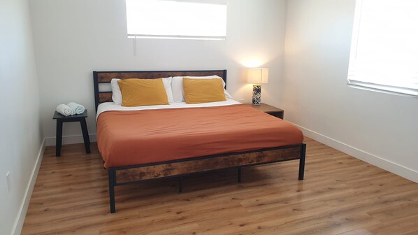 A bedroom with a wooden bed, white walls, and a window.