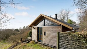 Une petite cabane en bois avec un toit en pente, une seule porte et une petite fenêtre.