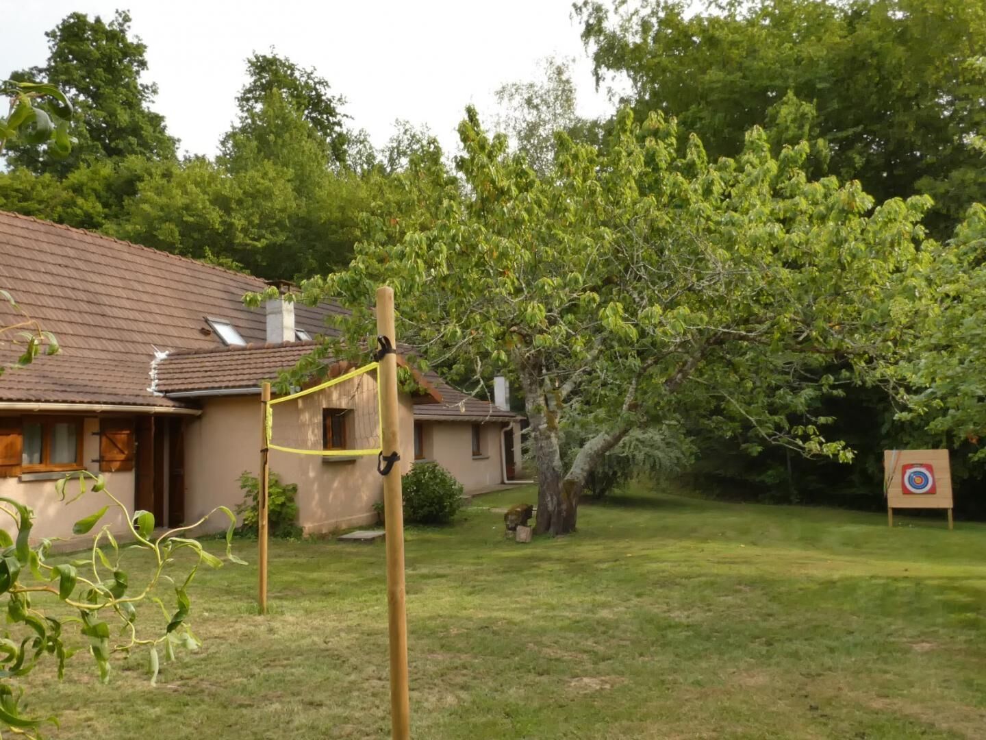 A house with a sloped roof, a fenced yard, and a tree in the background.
