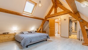 A bedroom with a bed, wooden beams, a skylight, and a staircase leading to another room. - Domaine du Venet - Montcony (MONTCONY)