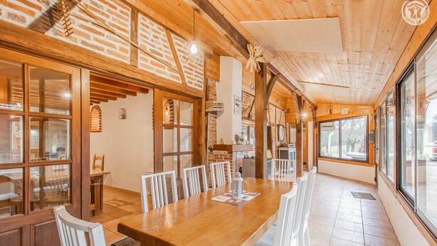 A spacious dining area with a long wooden table and white chairs, brick walls, and large windows providing natural light. - Domaine du Venet - Montcony (MONTCONY)